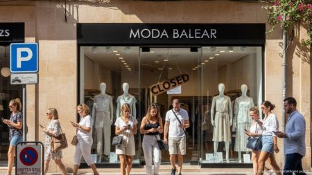 Straßenszene auf Mallorca mit ruhigem Modegeschäft und Passanten, die Kaufzurückhaltung und hohe Mieten im Einzelhandel darstellen