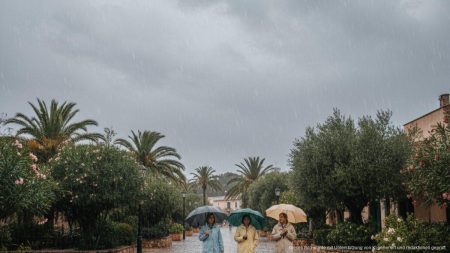 Regen und moderate Temperaturen in Santa Ponsa erwartet Realistisches Bild eines regnerischen Tages in Santa Ponsa auf Mallorca mit Menschen in Regenmänteln und Regenschirmen unter einer bewölkten, grauen Himmel
