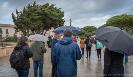 Windiger Tag in Santanyí, Mallorca mit Windjacken und Regenschirmen.