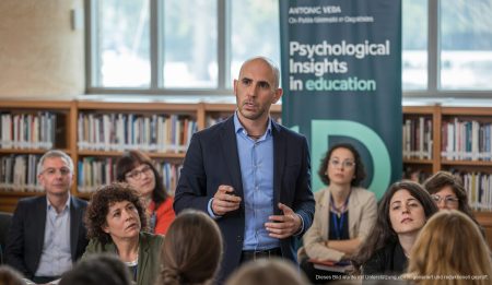 Antoni Vera hält einen Vortrag in einer Bibliothek, während Pädagogen aufmerksam zuhören.