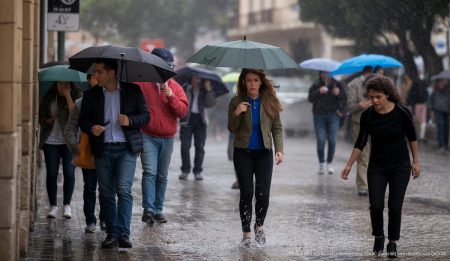 Starke Regenfälle und Wetterwarnung auf Mallorca erwartet Starker Regen auf Mallorca mit Menschen unter Regenschirmen in einer Stadt